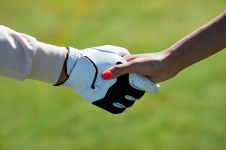 Closeup of two sports players shaking hands after game match outdoors against green grass backgroundの写真素材