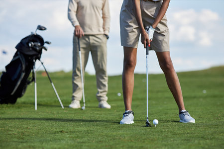 Low section of young woman playing golf on green grass and aiming for perfect shot, copy spaceの写真素材