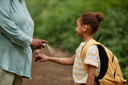 Side view of caring mother using baby safe bug repellent for daughter while travelling together in natureの写真素材