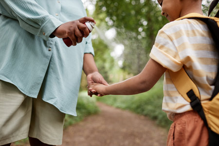 Close up of mother using baby safe bug repellent for daughter while hiking together in natureの写真素材