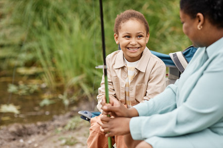 Portrait of little black girl smiling happily while enjoying fishing trip with parents, copy spaceの写真素材