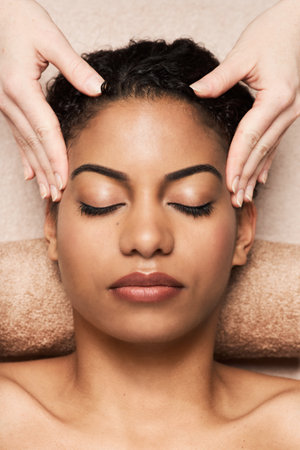 Black young woman getting relaxing head massage in beauty salonの写真素材