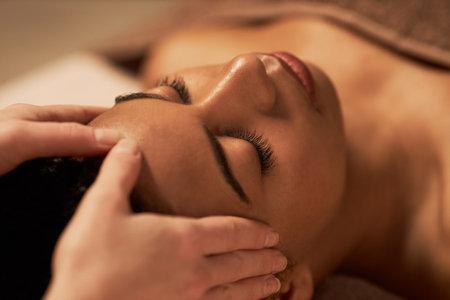 Young woman receiving face massage to get glowing and firm complexionの写真素材