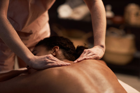 Masseuse massaging back of young woman with natural oilsの写真素材