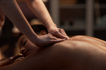 Therapist applying deep pressure when massaging back of young womanの写真素材