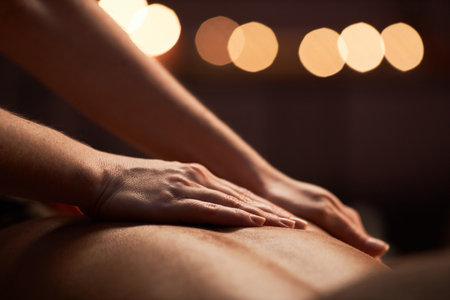 Closeup image of masseuse applying light strokes when applying oil on back of clientの写真素材