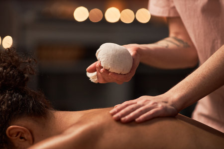 Young woman getting herbal bag massage to improve metabolismの写真素材