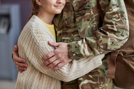 Close up of unrecognizable man wearing military uniform embracing daughter coming back homeの写真素材