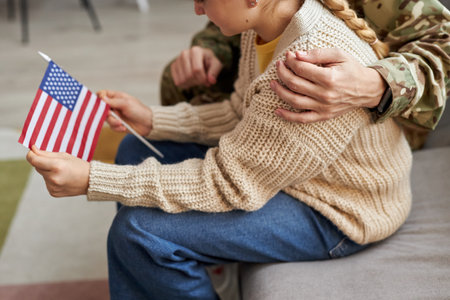 High angle closeup of teen girl holding American flag with military father, copy spaceの写真素材