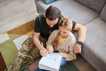 Top view of caring military father helping daughter doing homework and smilingの写真素材
