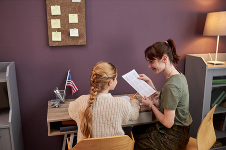 Back view of young mother working in military helping daughter with homework