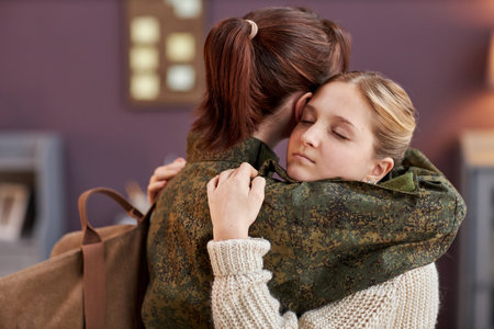 Side view portrait of teen girl embracing mother working in military with eyes closed, copy spaceの写真素材