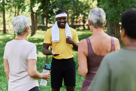 Portrait of smiling trainer talking to diverse group of senior women during outdoor sports workoutの写真素材