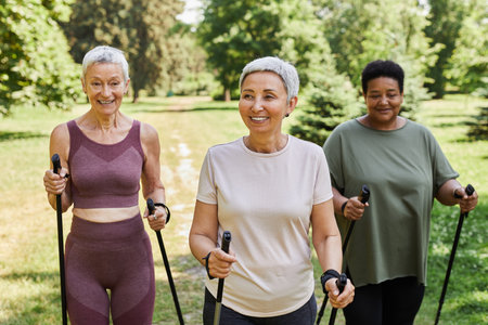 Group of active senior women walking with poles towards camera outdoors and smilingの写真素材