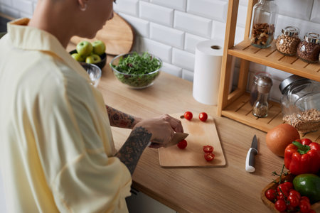 High angle closeup of tattooed woman cooking healthy meal and cutting vegetables in kitchenの写真素材