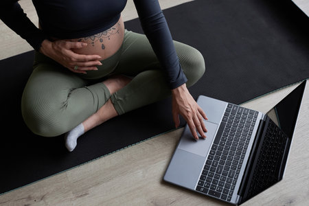 Close up of pregnant young woman using laptop ready for online prenatal yoga workout at home, copy spaceの写真素材