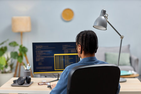 Back view of male IT professional writing code while working at office workplace, copy space