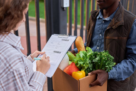 Closeup of young woman signing document accepting food delivery outdoorsの写真素材