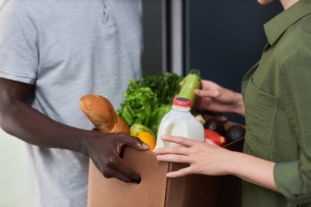 Close up of young woman accepting fresh grocery delivery to door at homeの写真素材