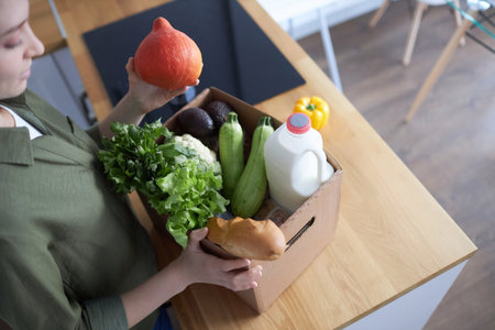 Top view closeup of young woman unpacking fresh groceries in kitchen, copy spaceの写真素材