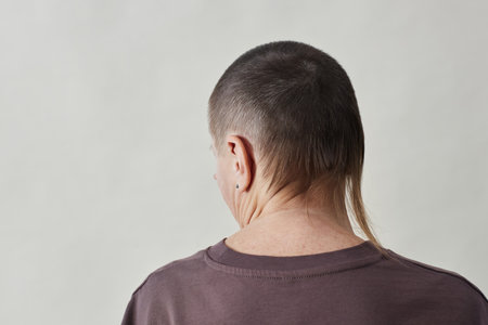 Minimal back view at mature bald woman struggling with alopecia, copy space