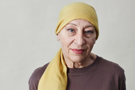 Front view portrait of smiling adult woman wearing headscarf and looking at camera against whiteの写真素材