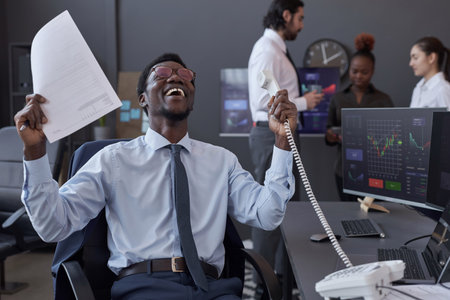 Successful broker winning the deal during phone conversation at his workplaceの写真素材