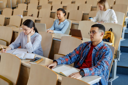 Group of students sitting at desk with books in lecture hall and studying at universityの写真素材