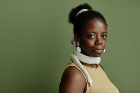 Young African American pretty woman with hair bun and snake enlacing her neck looking at camera...