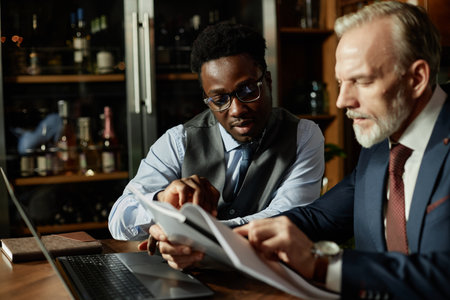 Two business partners examining contract sitting at table during their meeting in restaurant
