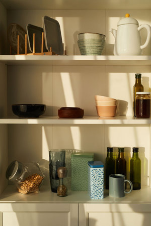 Vertical image of cupboard with kitchen utensils on the shelves in the kitchenの写真素材