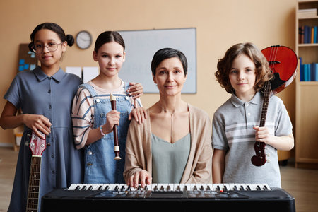 Portrait of teacher sitting at piano and looking at camera together with children in music classの写真素材