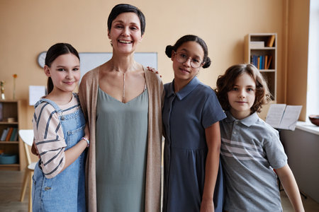Portrait of happy music teacher smiling at camera while standing with her students in music classの写真素材