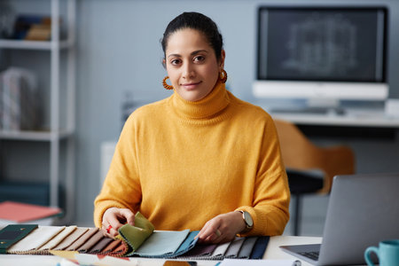 Portrait of young designer looking at camera while working with palette at her workplace in officeの写真素材