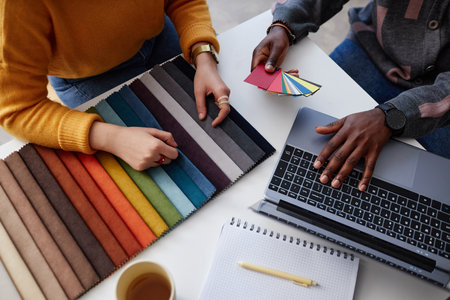 High angle view of two designers choosing colour for interior and working with project online on laptopの写真素材