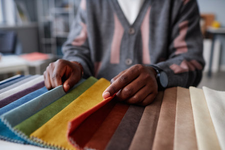 Close-up of African American designer choosing colour for interior while sitting at tableの写真素材