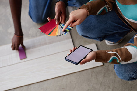 High angle view of designer choosing color for flooring together with customer using palette and smartphoneの写真素材