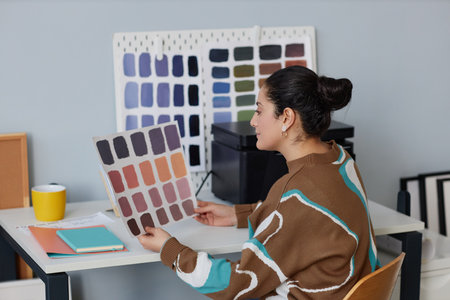 Designer examining color pattern while sitting at her workplace in office