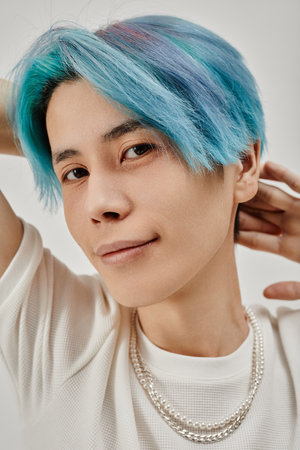 Vertical image of Asian young man with blue hair looking at camera