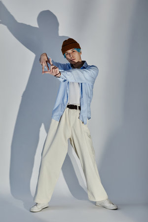 Vertical image of young guy in stylish clothing posing and gesturing at camera against white...