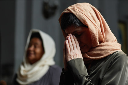 Mature woman with headscarf on her head praying during her visit in churchの写真素材