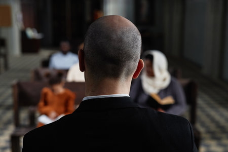 Rear view of protestant in black suit reading Bible for believers while they sitting on bench in baptist churchの写真素材