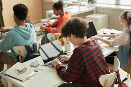High angle view at teenage schoolboy using laptop in programming class for children