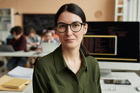 Young woman as female teacher in programming class for children looking at cameraの写真素材