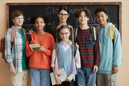 Front view portrait of diverse group of children looking at camera standing by blackboard in classの写真素材