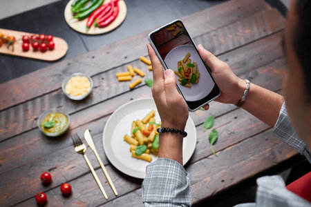 High angle view of photographer making photo of pasta on smartphone for his food blogの写真素材