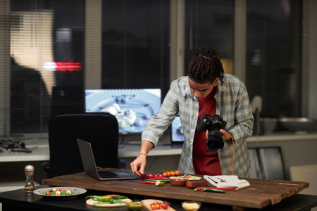 Young photographer concentrating on shooting food with professional camera in studio