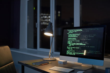Workplace of programmer with computer monitor in dark office