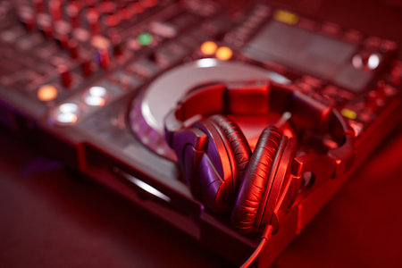 Closeup of DJ equipment, mixer or turntable in neon light with studio headphones, copy spaceの写真素材