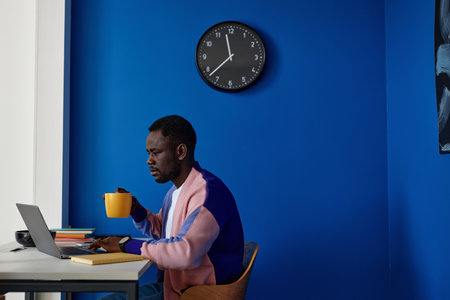 Contrasted side view portrait of young woman using laptop at workplace in office with vibrant...